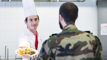 A sodexo employee handing clean uniforms to a member of the armed forces