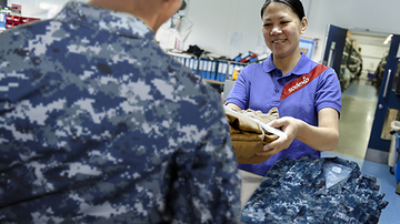 A sodexo employee handing a clean uniform to a soldier